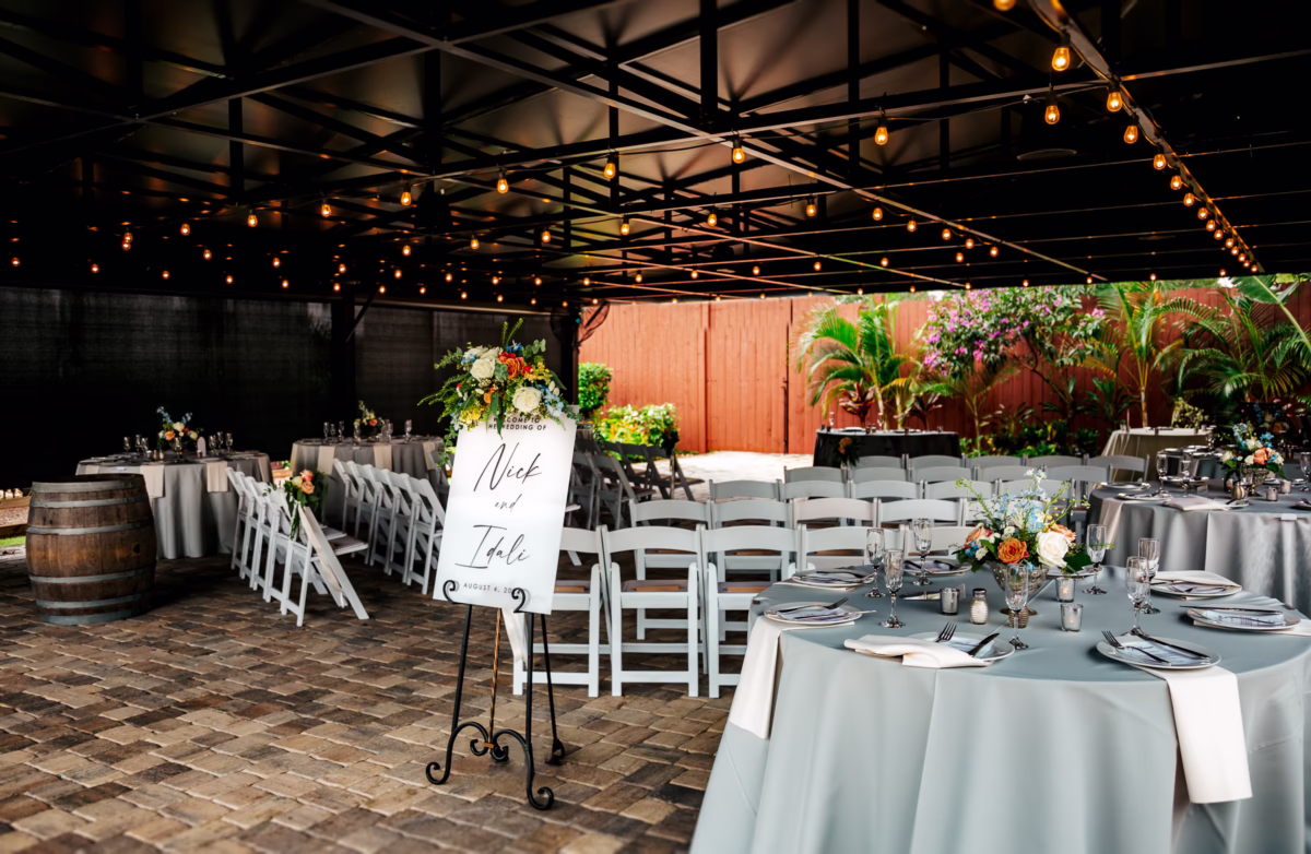 orlando celebration gardens wedding reception setup string lights floral centerpieces winter park - Weddings Elegant outdoor wedding reception setup at Orlando Celebration Gardens in Winter Park featuring round tables with light blue linens, floral centerpieces, white chiavari chairs, and romantic string lights overhead creating an intimate dining atmosphere
