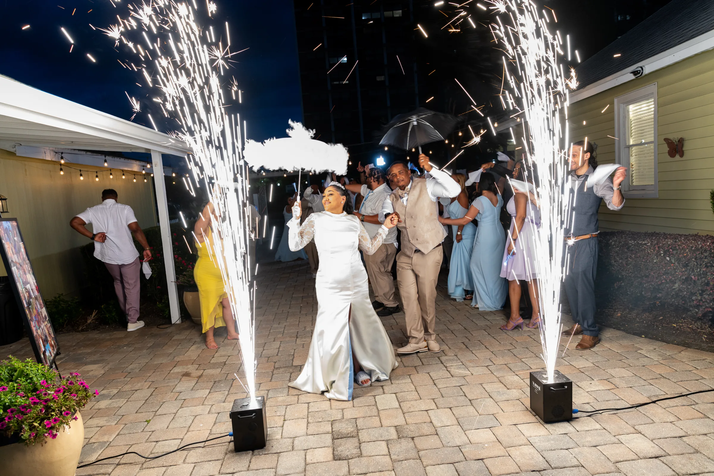 Bride and groom walk through a dramatic cold sparkler exit during a New Orleans-style Second Line wedding celebration, surrounded by guests in blue bridesmaid dresses