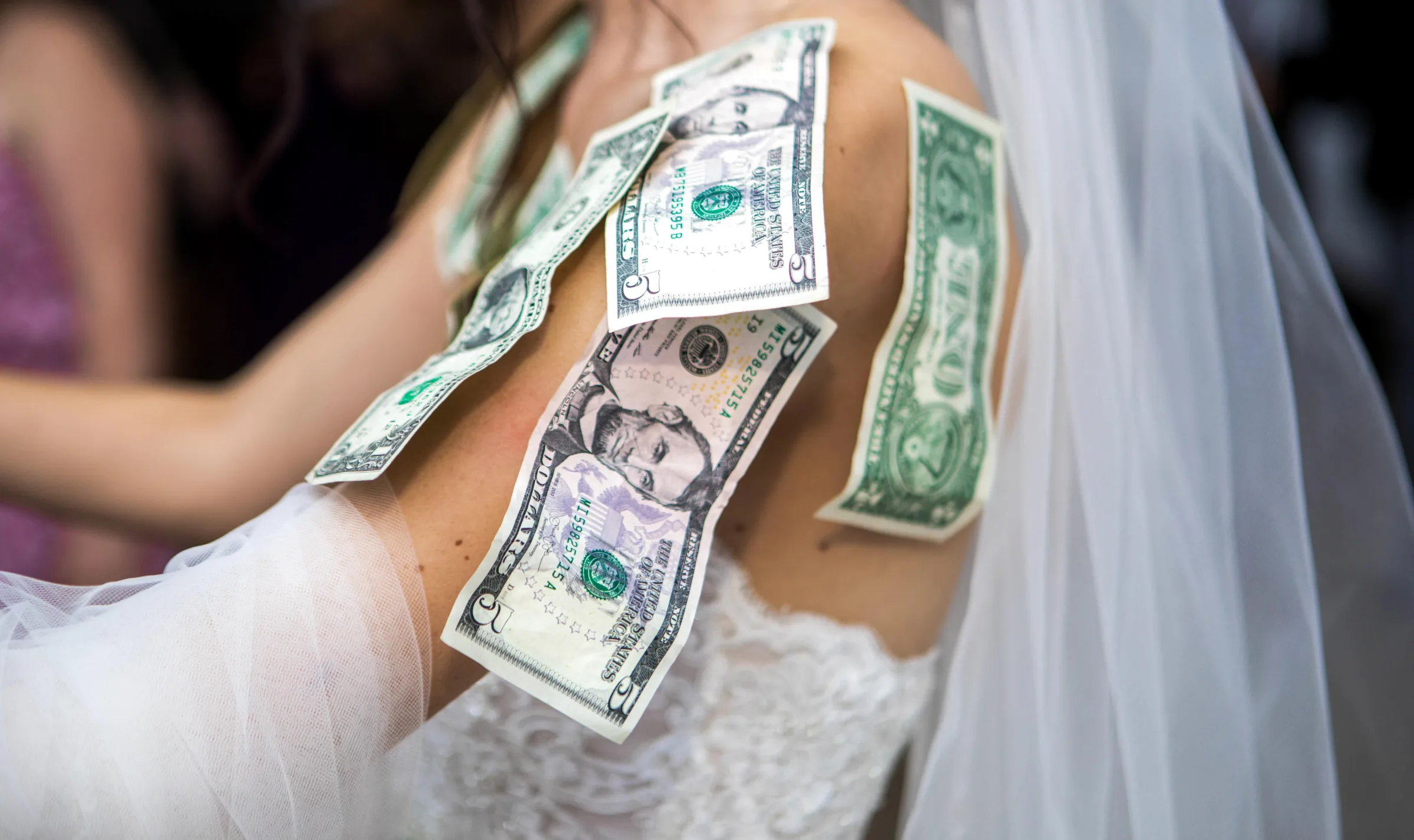 Dollar bills pinned to a bride's white wedding gown during the traditional money dance