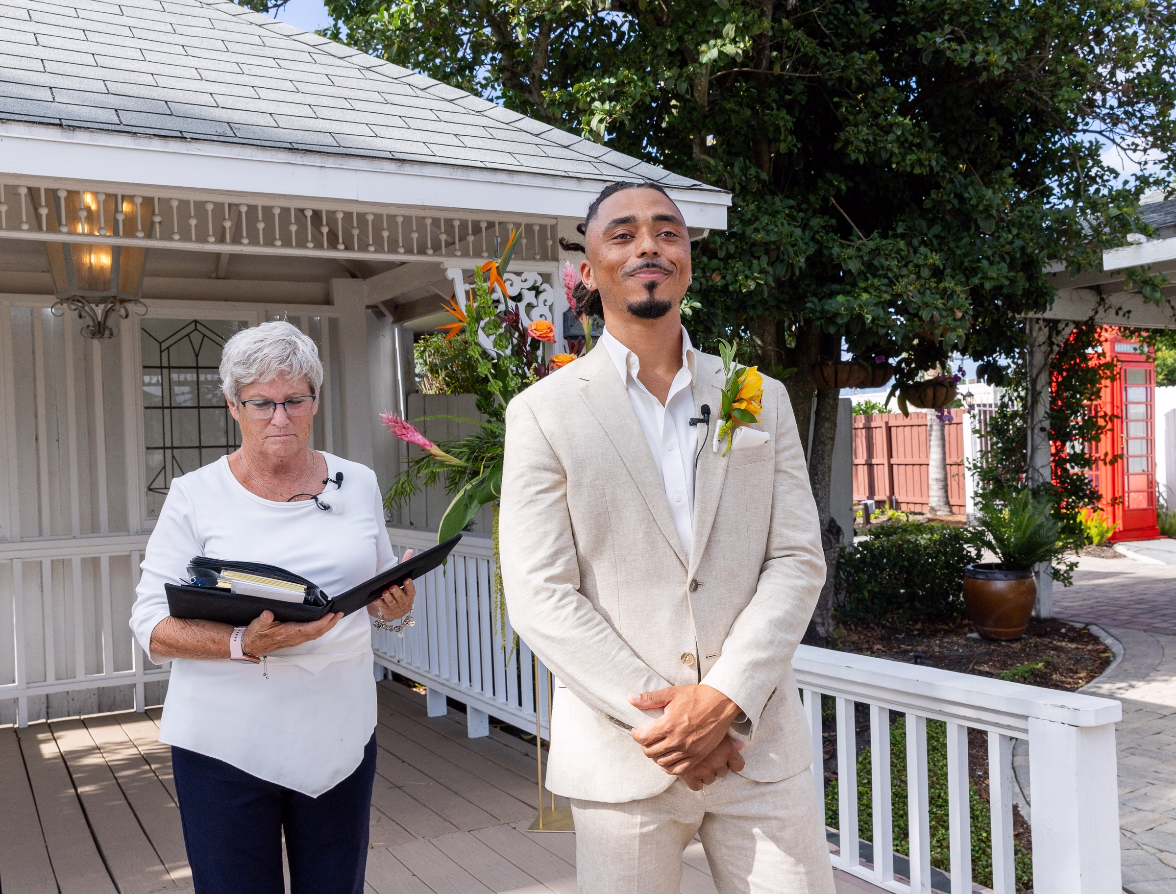 Groom in a beige linen suit with sunflower boutonniere stands at the altar during an outdoor wedding ceremony officiated at Orlando Celebration Gardens in Orlando Florida