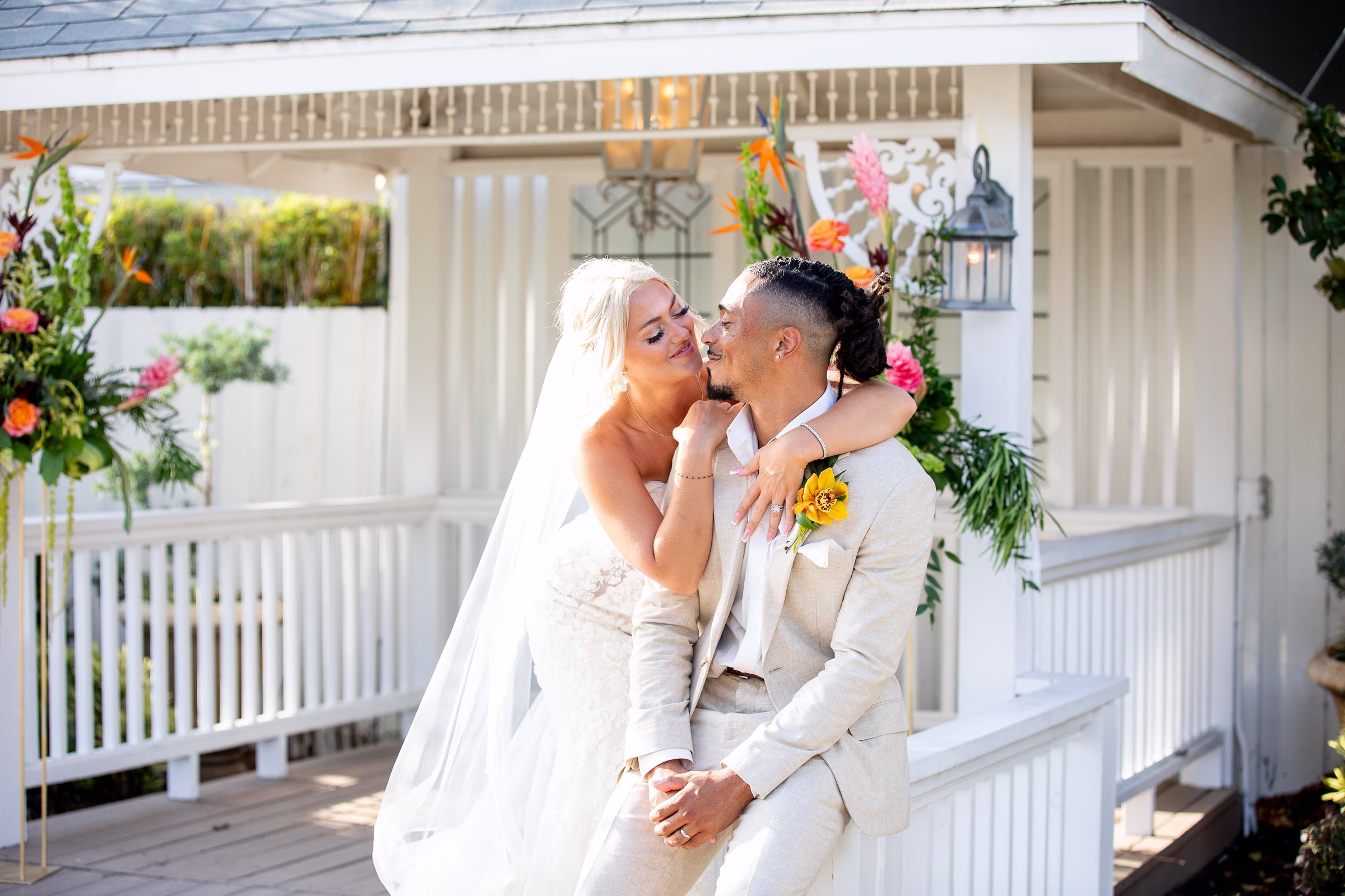 Bride in white gown and veil embraces groom in beige suit with tropical yellow orchid boutonniere at Orlando Celebration Gardens wedding venue in Orlando Florida
