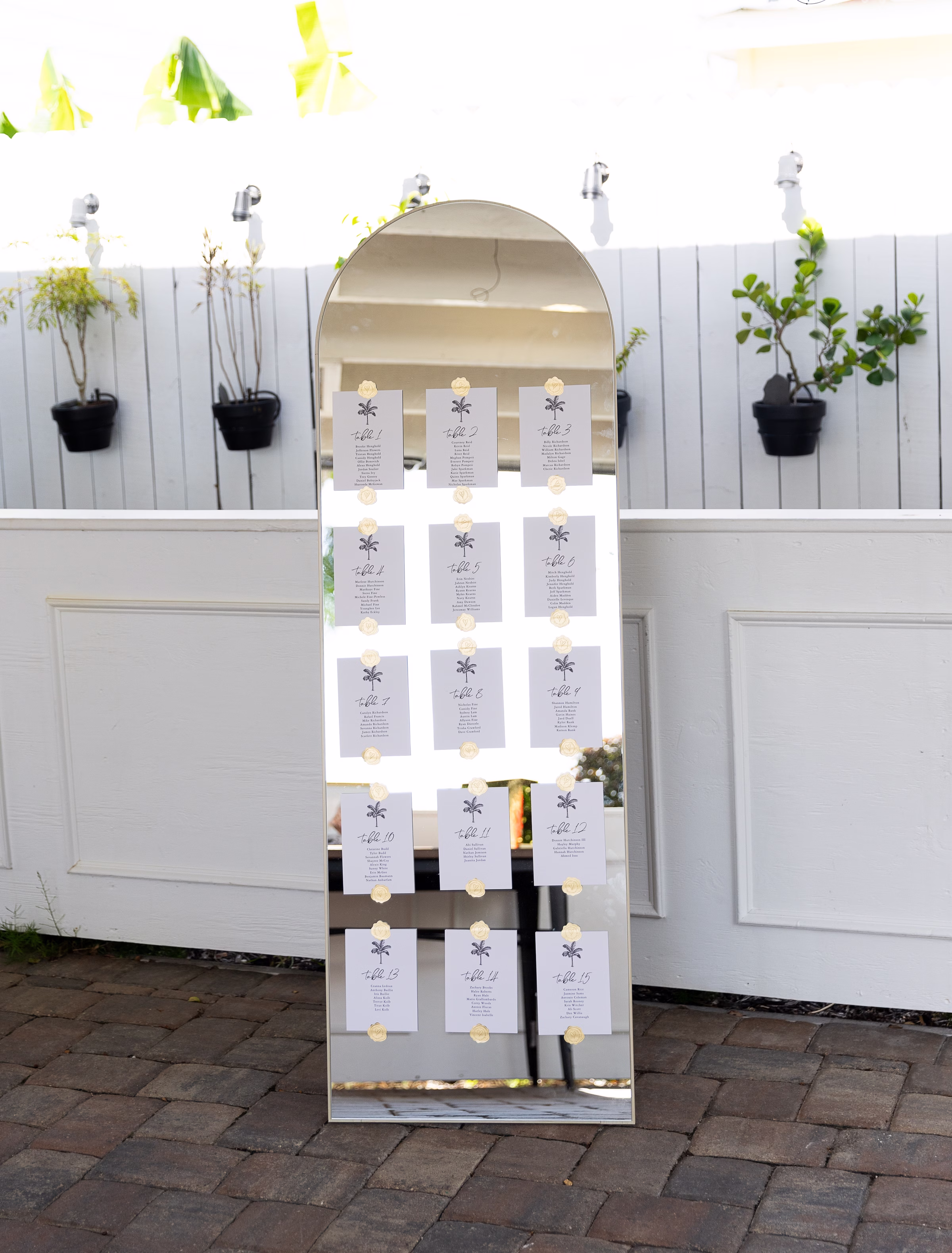 Elegant arched mirror wedding seating chart display with palm tree table assignment cards at Celebration Gardens wedding venue in Orlando Florida